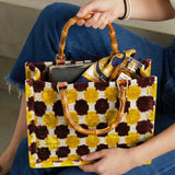 Person holding a patterned handbag with wooden handles
